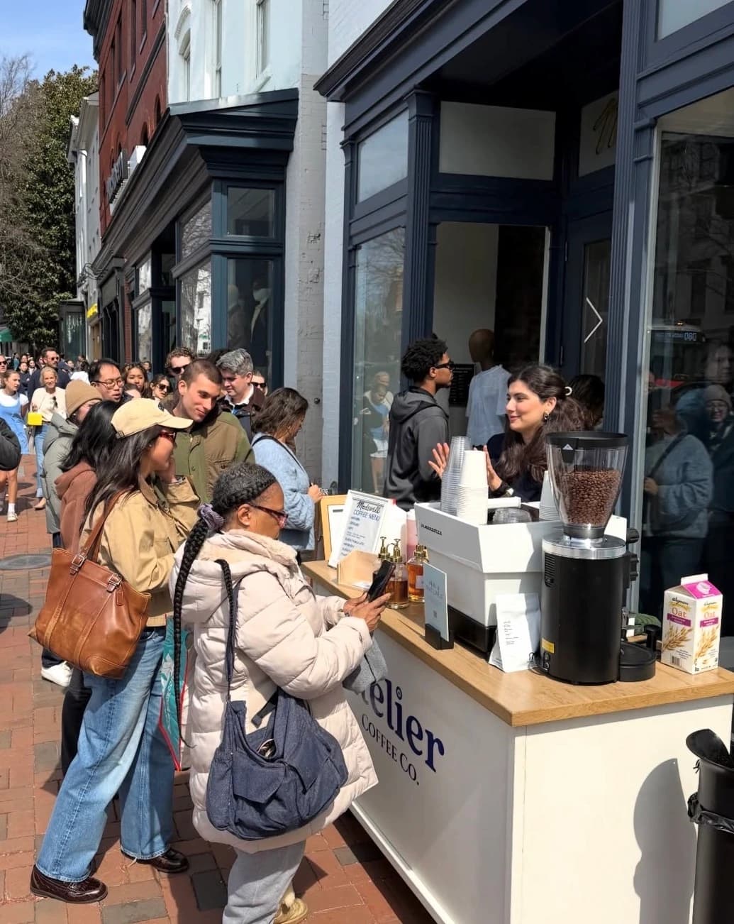 Morning queue at a sidewalk espresso cart while the barista chats with customers