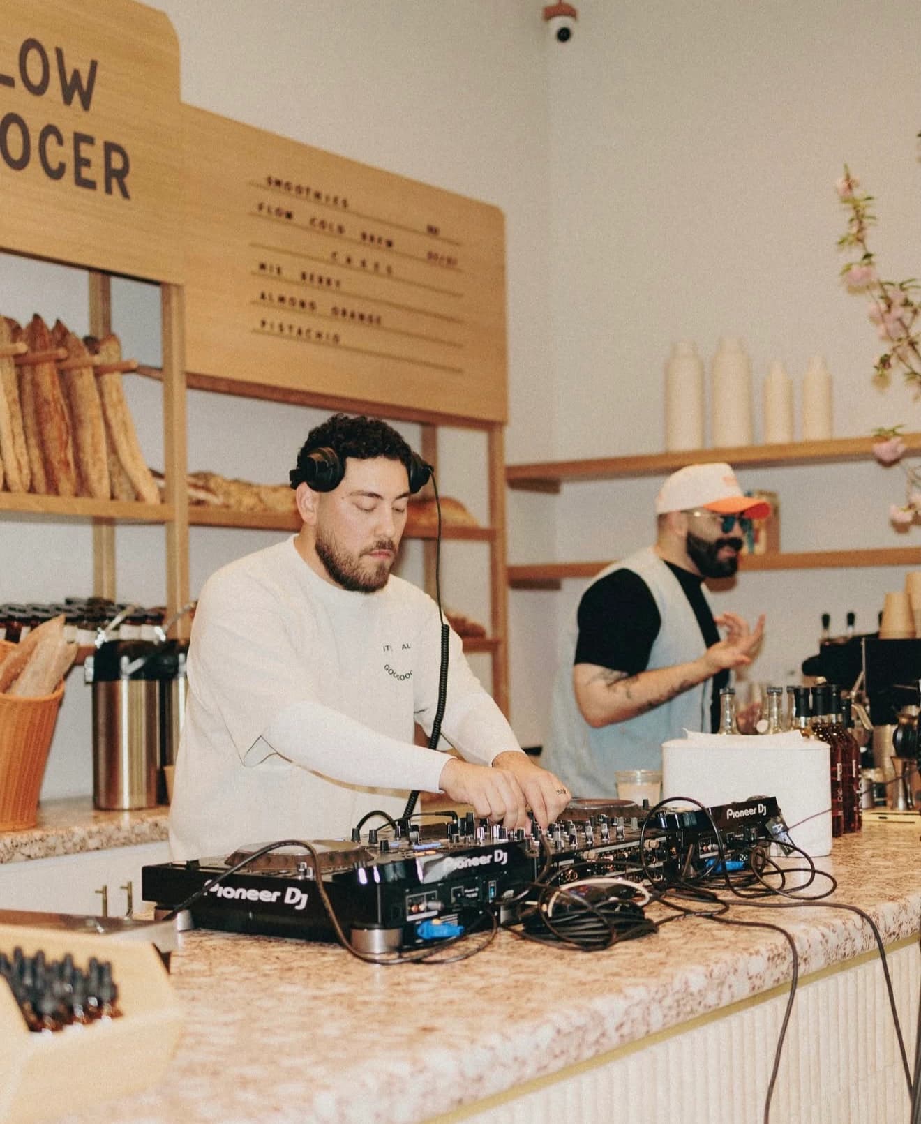 DJ spinning records behind the counter of a neighborhood grocer café