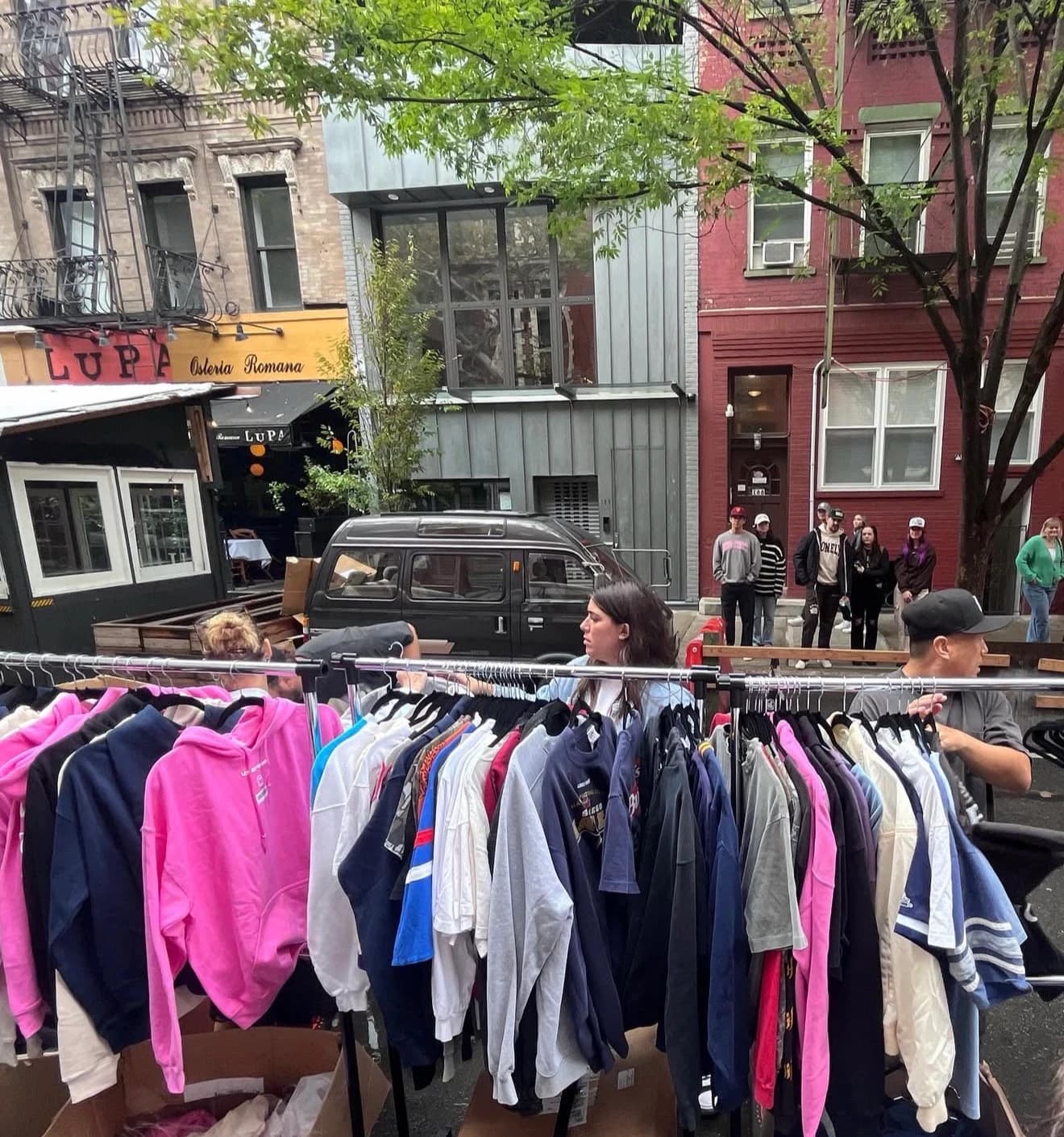 Shopper browsing a rack of vintage clothes at a street pop-up