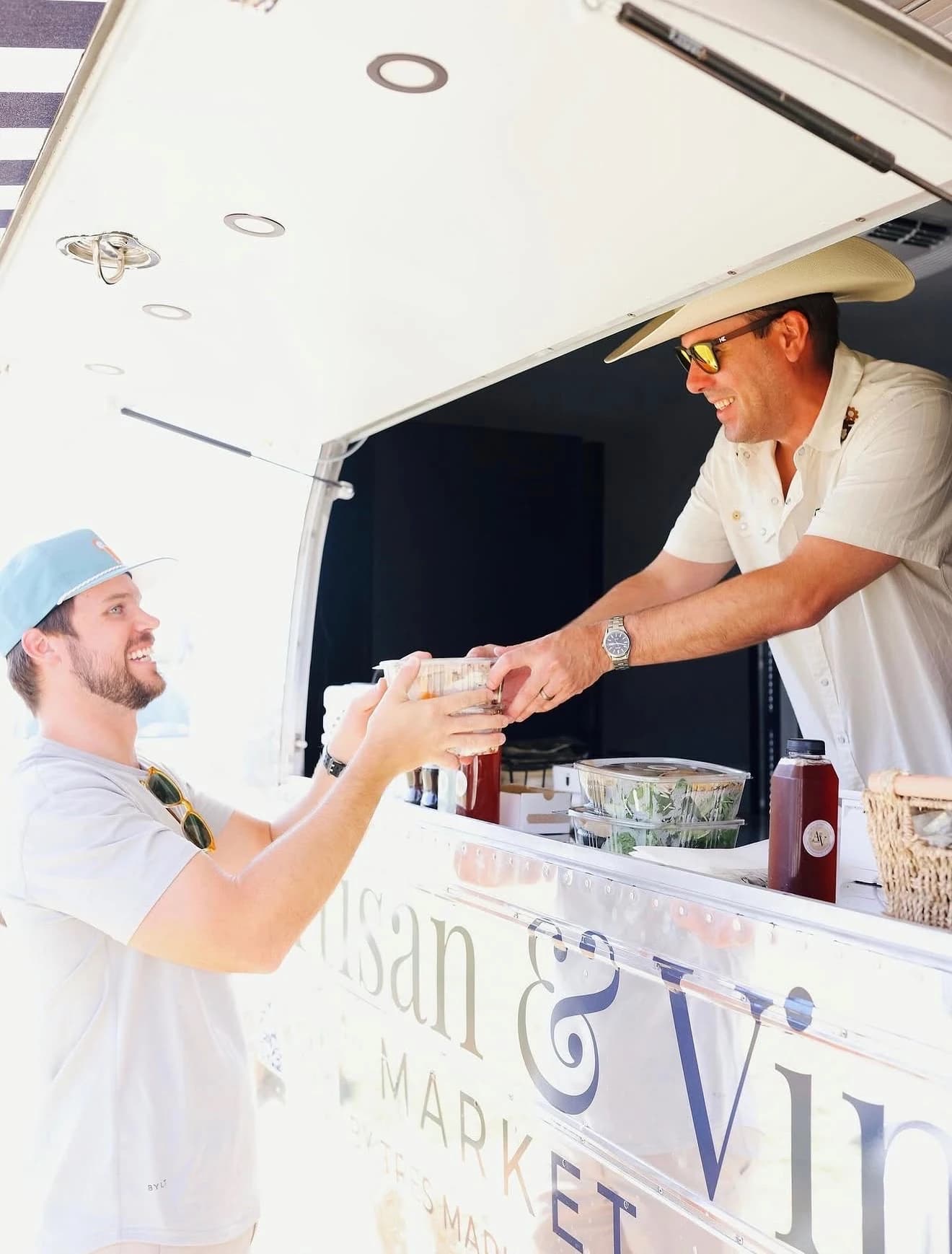 Food-truck vendor handing a fresh order to a customer at the window